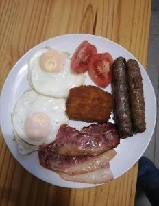 a plate of breakfast food with eggs sausage and tomatoes at Swartberg Guest House in Caledon