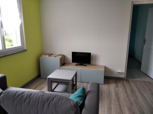 a living room with a couch and a tv at Les figères - Les gites de Pierregras in Vals-les-Bains