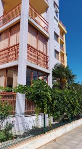 a building with a fence and a tree in front of it at Апартамент Златна дюна-Фешева in Nesebar