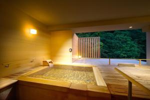 bañera de hidromasaje en una habitación con ventana grande en Hakone Pax Yoshino en Hakone