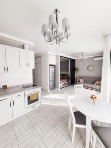 a white kitchen with a table and a dining room at Apartments Park Fountains in Liski