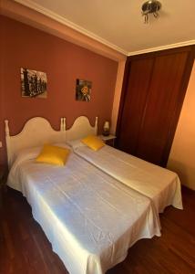um quarto com uma grande cama branca com almofadas amarelas em Albergue Buen Camino em Navarrete