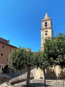 een gebouw met een toren met een boom ervoor bij Albergue Buen Camino in Navarrete