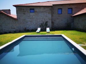 a swimming pool with two chairs and a house at Casa da Portela - Sem Igual in Meinedo