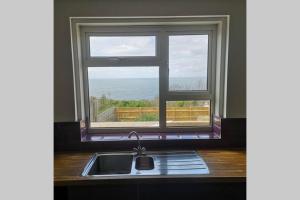 a kitchen sink and a window with a view of the ocean at Chesil View in Castletown +17 photos