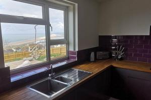 a kitchen with a sink and a large window at Chesil View in Castletown