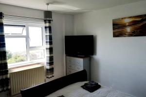 a bedroom with a bed and a flat screen tv at Chesil View in Castletown