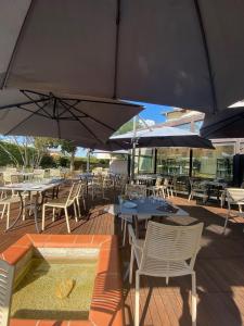 un patio con mesas, sillas y sombrillas en Hotel L'Hotan en Portet-sur-Garonne