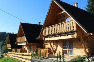 uma cabana de madeira com um telhado preto em Chałupy Na Brzyzku em Poronin