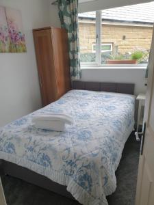 a bedroom with a bed with a blue and white comforter at Horseshoe Forge Plover Cottage Lindley in Huddersfield