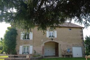 uma grande casa de tijolos com uma porta e uma árvore em Appartement spacieux au coeur de la nature em Fougerolles