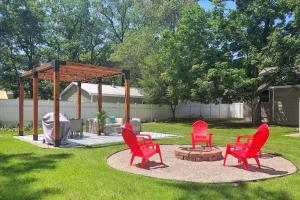 drie rode stoelen en een vuurplaats in een tuin bij Bohemian Retreat in Traverse City