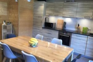 eine Küche mit einem Holztisch mit Stühlen und einer Theke in der Unterkunft Modern Comfortable Chalet with large terrace in Morzine