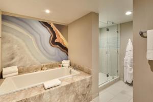 a bathroom with a tub, sink, mirror and bathtub at Loews Santa Monica Beach Hotel in Los Angeles
