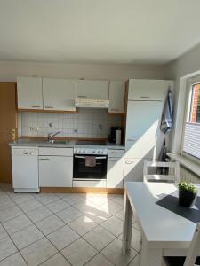 een keuken met witte kasten, een wastafel en een tafel bij Wohnung auf dem Lande in Riepsdorf