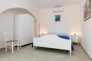 biała sypialnia z białym łóżkiem i dwoma stołami w obiekcie casa vacanza Rosy di Guida Rosy w mieście Giungano