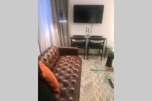 a living room with a brown leather couch and a table at Luxurious Studio in the heart of Cape Town CBD in Cape Town