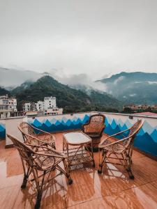 four chairs and a table on a balcony with a view at Joey's Hostel Rishikesh in Rishīkesh