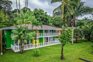 a green house with palm trees in front of it at Tortuga Lodge & Gardens in Tortuguero