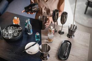 a person holding a bottle of alcohol and cups on a table at AEON Hotel - adults only Bed & Breakfast in Soprabolzano