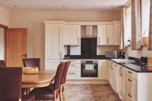 a kitchen with white cabinets and a wooden table at Cleeton Cottage in Elmbridge