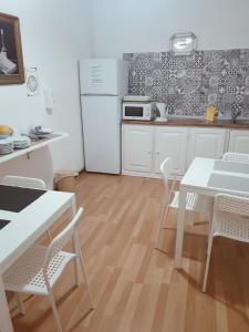 a kitchen with a white refrigerator and a table and chairs at Hospedaria Pôr do Sol in Funchal