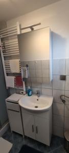 a white bathroom with a sink and a mirror at Apartments Plavčić in Plomin