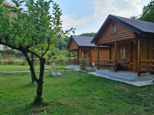 a log cabin with a tree in the yard at Little Paradise in Virpazar