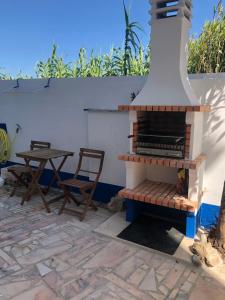 einen Außenkamin mit einem Tisch und Stühlen auf einer Terrasse in der Unterkunft Villa Praia in São Martinho do Porto