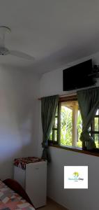 1 dormitorio con ventana y TV de pantalla plana en Beautiful day suítes, en Ilhabela