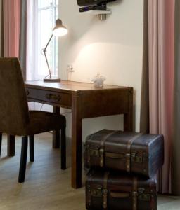 a desk with a chair and a chair with a table and suitcase at Hôtel du Haut Koenigsbourg- entre vignes et château in Thannenkirch