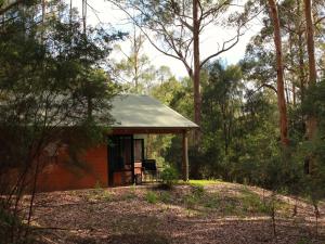 a small red house with a porch in the woods at Marima Cottages in Pemberton