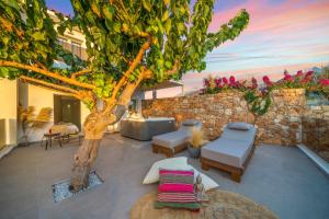 a patio with a tree and a stone wall at Notos Heights Hotel & Suites in Malia