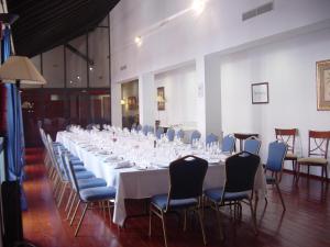 una mesa larga con mesas blancas y sillas en una habitación en Hotel Escuela Convento Sto Domingo en Archidona