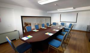 una sala de conferencias con una mesa larga y sillas azules en Hotel Escuela Convento Sto Domingo en Archidona