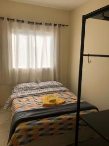 um quarto com uma cama, uma janela e uma colcha. em Apartamento com varanda em Lavras