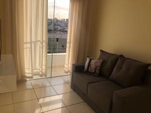 uma sala de estar com um sofá e uma grande janela em Apartamento com varanda em Lavras