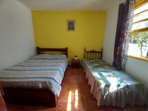 two beds in a room with yellow walls at Infinito House - Casa inteira in São Paulo