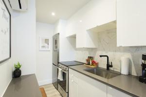 a kitchen with white cabinets and a sink at Serene and Styled Little Italy Studio full bath by Den Stays in Montréal +36 photos