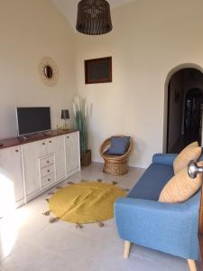 un salon avec un canapé bleu et une télévision dans l'établissement Different House Holidays, à Fuzeta