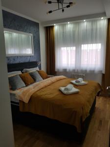 - une chambre avec un grand lit et des serviettes dans l'établissement LUX APARTMENT SANJA 3, à Subotica