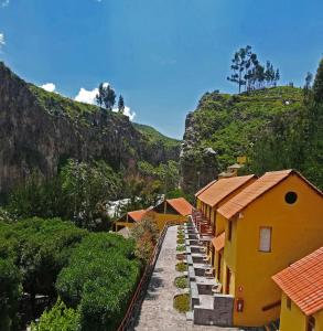 eine Gruppe von Gebäuden auf einem Hügel mit einem Berg in der Unterkunft Hotel El Refugio in Chivay