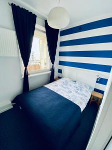 1 dormitorio con una pared de rayas azul y blanco en Apartament Il Capitano, en Gdynia