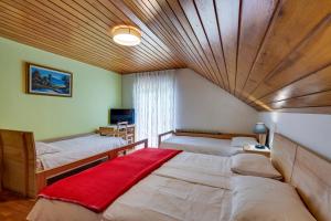a bedroom with two beds and a wooden ceiling at Rooms Pevc & Hostel Ljubno ob Savinji in Ljubno