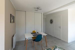 a white room with a table and chairs at Studio Cosy avec balcon et garage privé in Le Mans