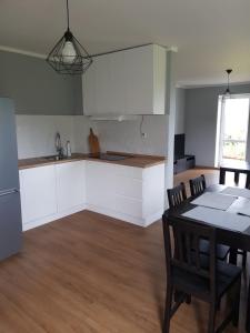 a kitchen with white cabinets and a table and chairs at Apartament Wydminy in Wydminy