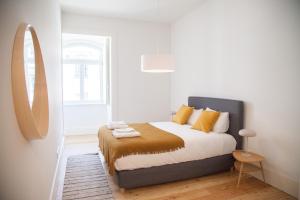 sypialnia z łóżkiem z żółtymi poduszkami i lustrem w obiekcie FLH Praça Comércio Wood Design Flat w Lizbonie