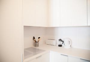 a white kitchen with white cabinets and a microwave at FLH Praça Comércio Wood Design Flat in Lisbon