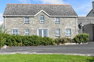 a large stone house with a garage at Aran View Holiday Home in Doolin