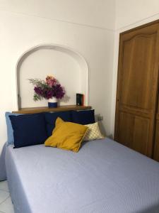 1 dormitorio con 1 cama azul y un jarrón de flores en Capri Sun, en Anacapri